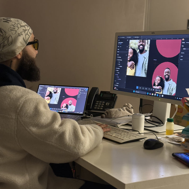Fady sitting at a desk with two computer monitors, displaying he is designing PPB's personalized ping pong balls