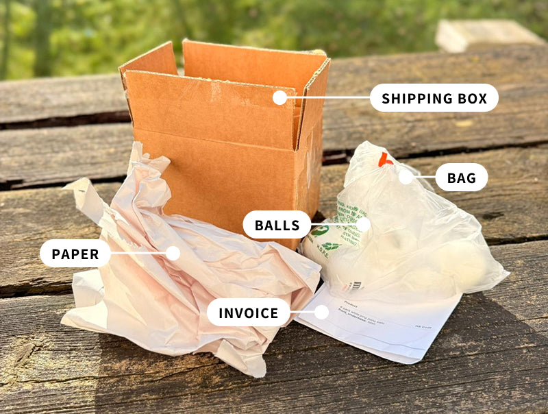 Image showing how PPB's print provider ships each set: shipping box, filling paper, personalized ping pong balls, and an invoice on a wooden surface.